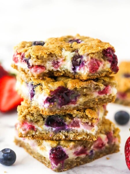 A stack of berry oatmeal cheesecake bars. The top one has a bite taken out of it.