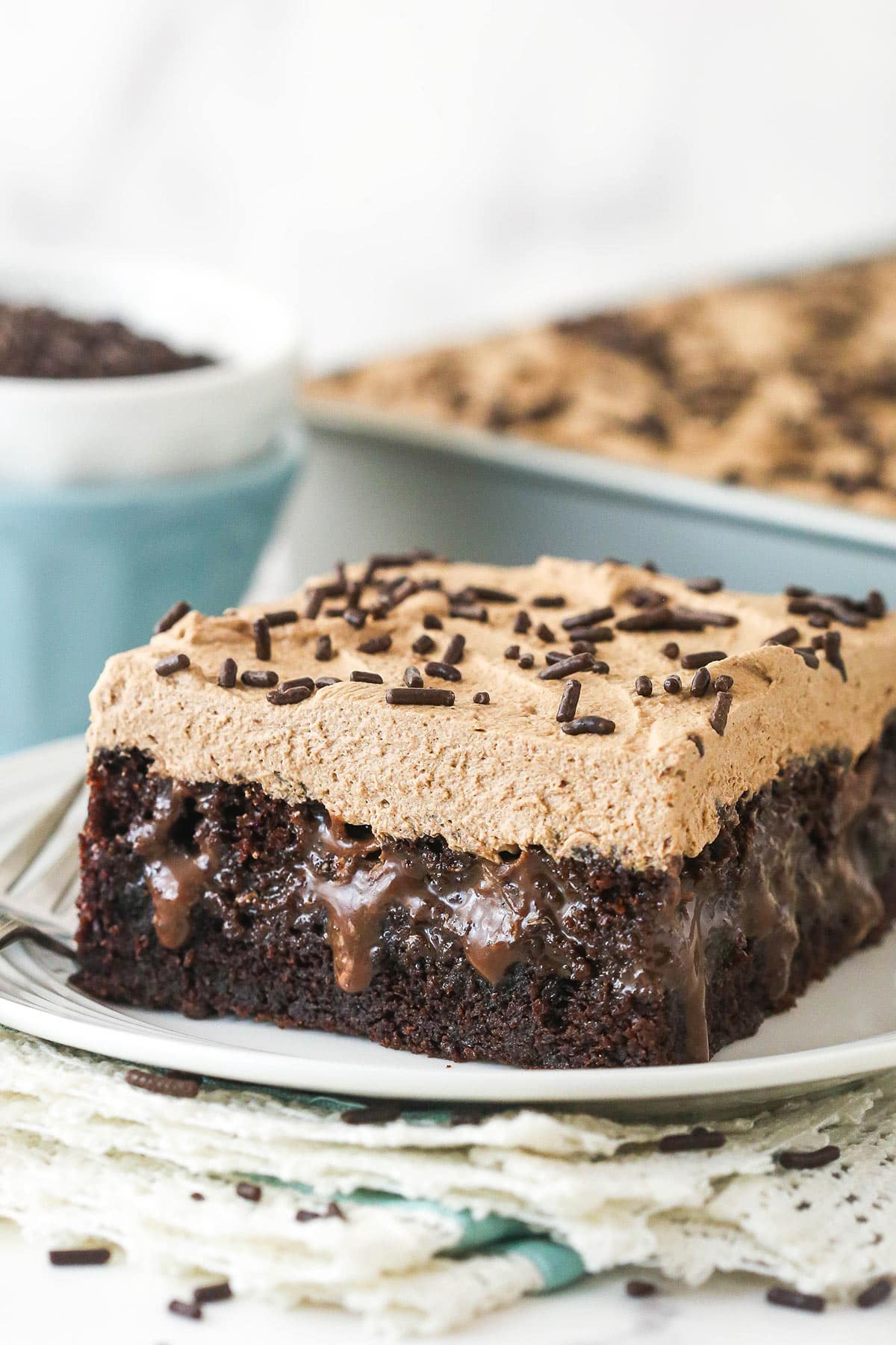 Closeup of a slice of chocolate poke cake on a plate.