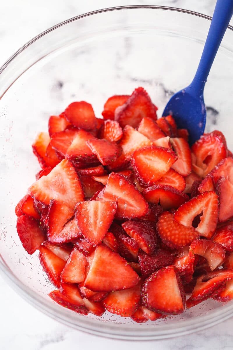 This strawberry shortcake recipe turns out cute, individual desserts made of flaky biscuits stuffed with juicy strawberries and whipped cream. Tossing strawberry slices with sugar.