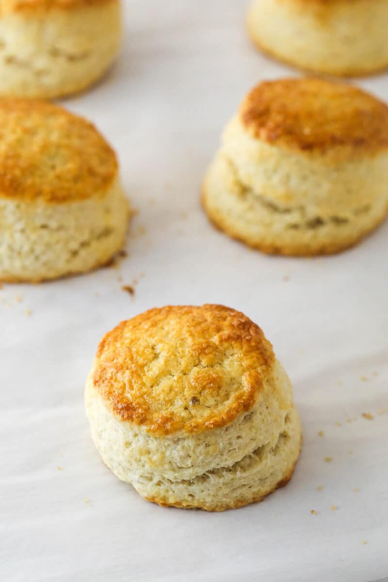 This strawberry shortcake recipe turns out cute, individual desserts made of flaky biscuits stuffed with juicy strawberries and whipped cream. Shortcake biscuits on parchment paper.