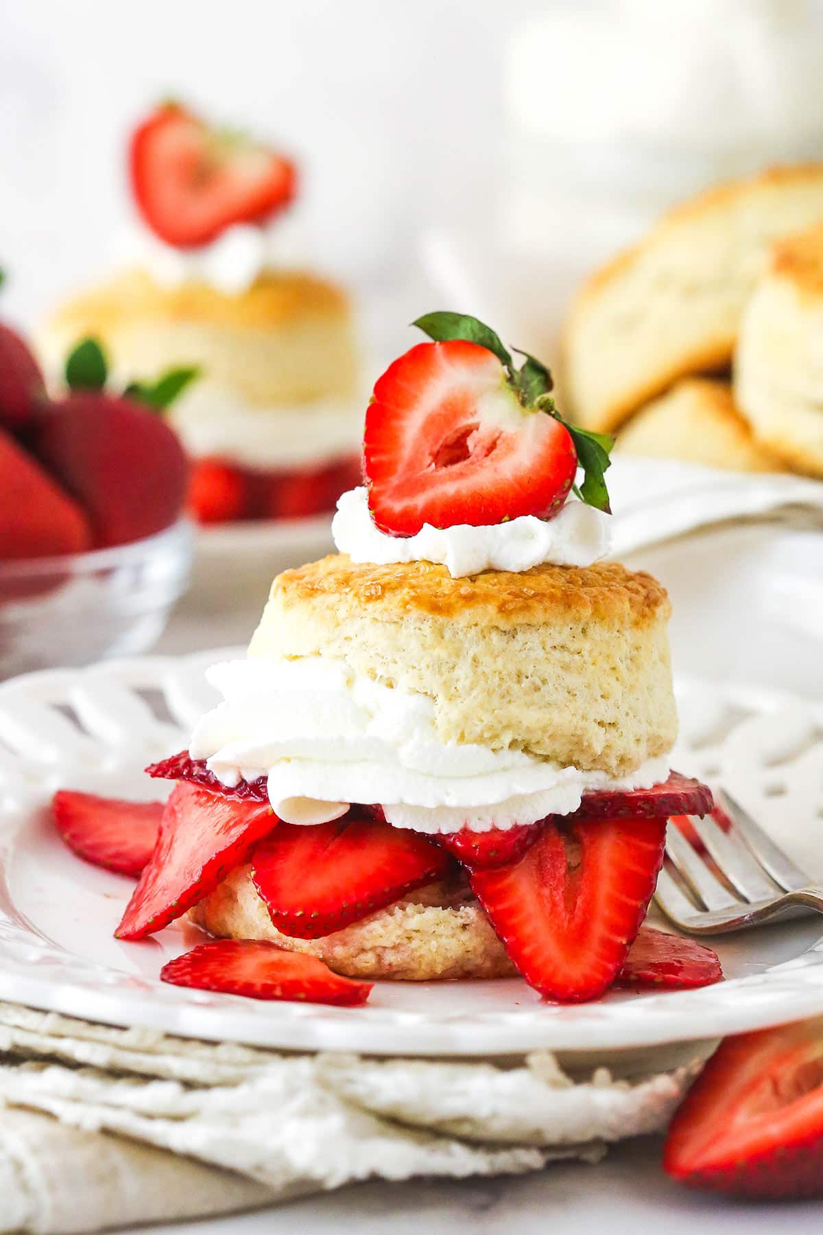 This strawberry shortcake recipe turns out cute, individual desserts made of flaky biscuits stuffed with juicy strawberries and whipped cream. Strawberry shortcake on a plate with a fork.