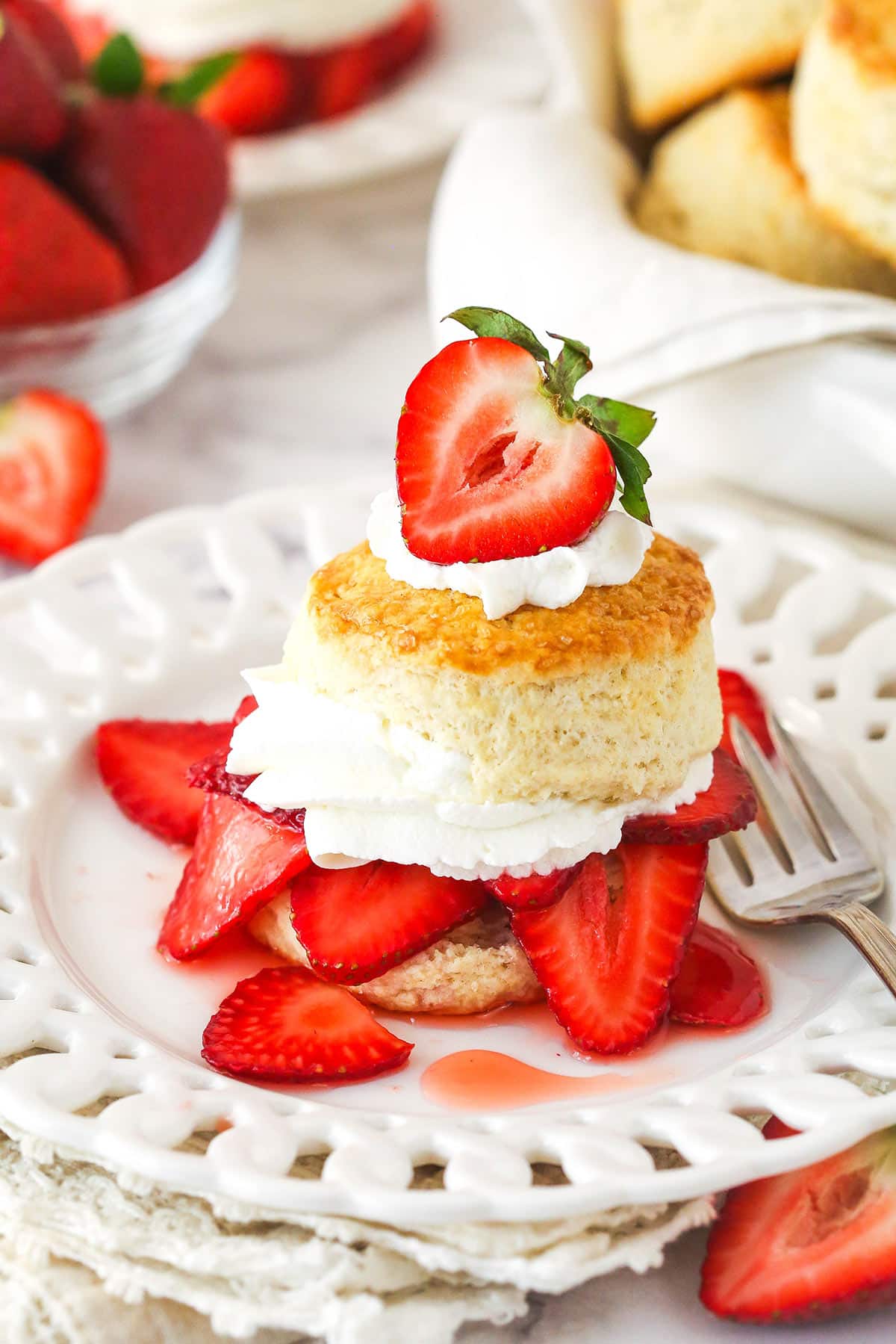 This strawberry shortcake recipe turns out cute, individual desserts made of flaky biscuits stuffed with juicy strawberries and whipped cream. Strawberry shortcake served on a plate.