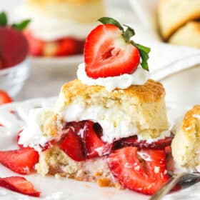 Strawberry shortcake on a plate with a couple of bites taken out of it.