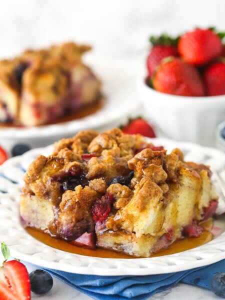 A slice of berry French toast casserole served on a plate with maple syrup.