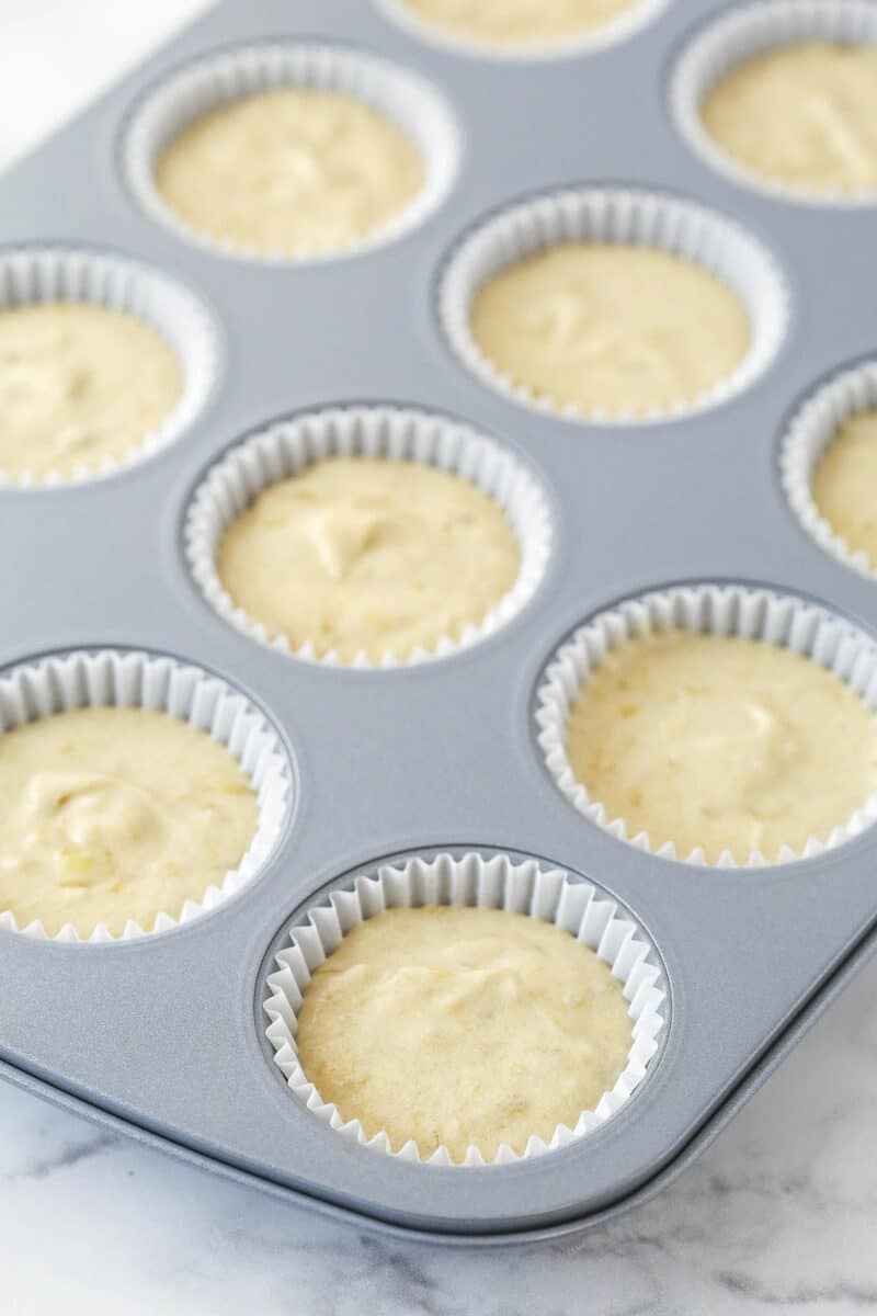 Filling lined cupcake tins with banana cupcake batter.