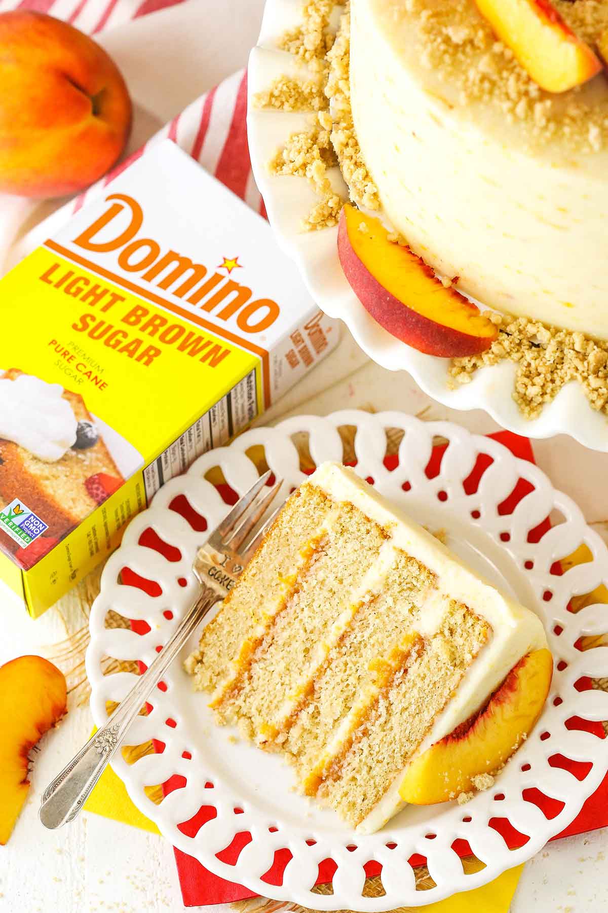 A slice of Brown Sugar Layer Cake With Peach Filling on a white plate next to a box of Domino Sugar