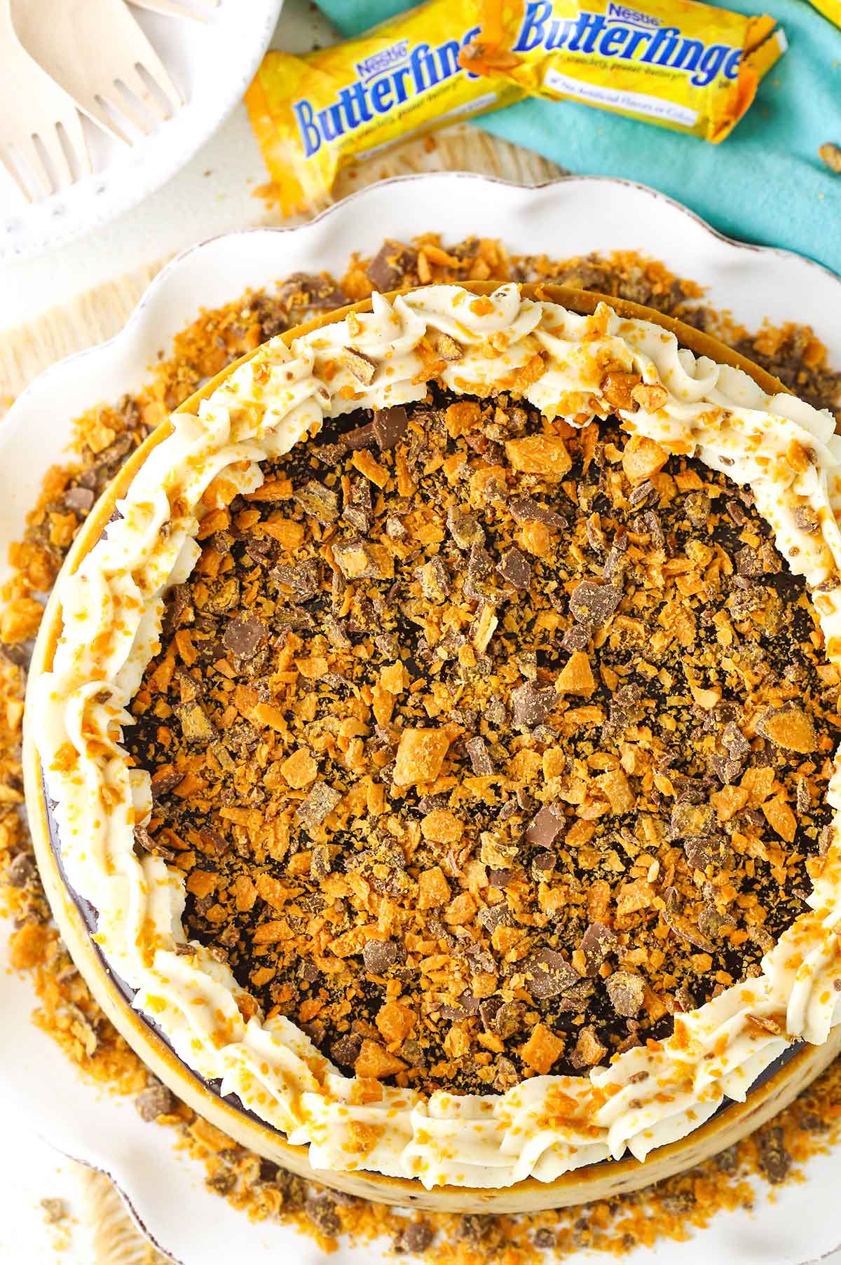 Overhead view of a full Butterfinger Cheesecake on a white cake stand