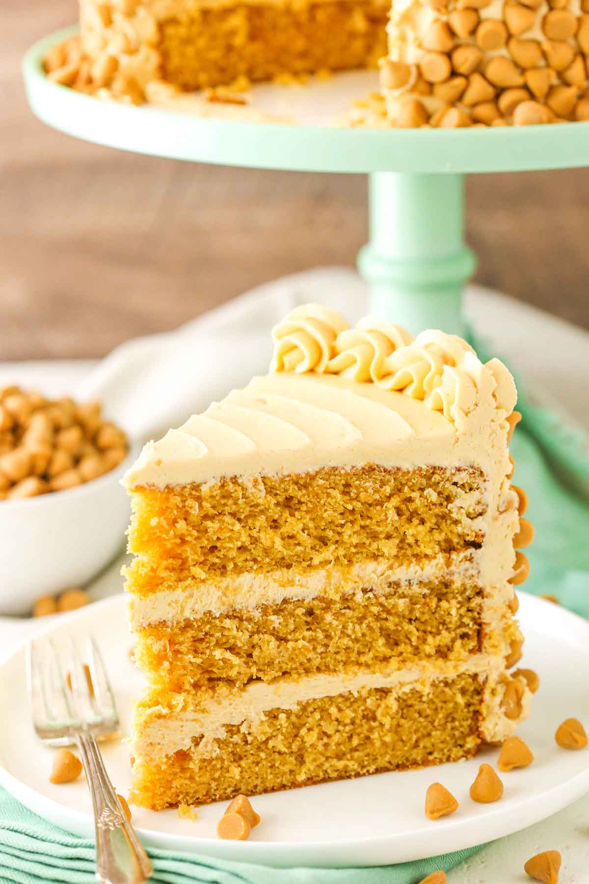 A slice of Ultimate Butterscotch Cake next to a fork on a white plate