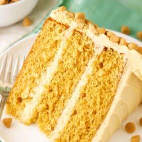 A slice of Ultimate Butterscotch Cake next to a fork on a white plate