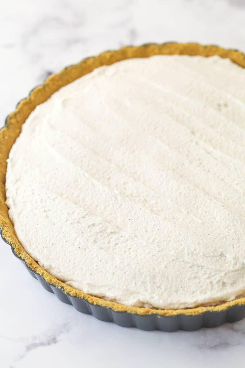 With a hint of cinnamon and some mini chocolate chips, this cannoli tart has all the great flavors of a cannoli wrapped into one simple tart. Spreading the ricotta filling for cannoli tart into a graham cracker crust.