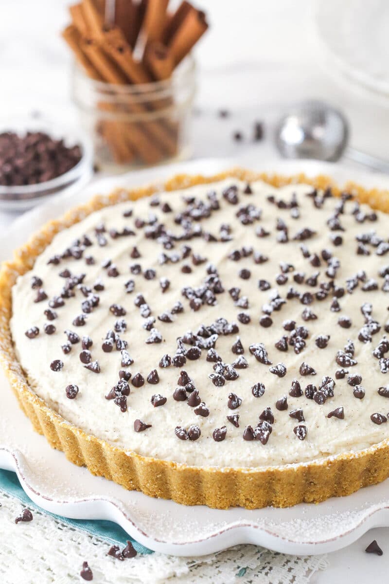 With a hint of cinnamon and some mini chocolate chips, this cannoli tart has all the great flavors of a cannoli wrapped into one simple tart. Cannoli tart on a serving platter.