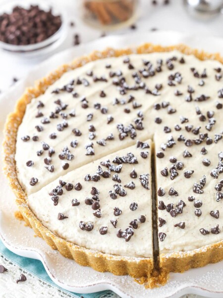 Cannoli tart on a serving platter with a slice cut and ready to serve.
