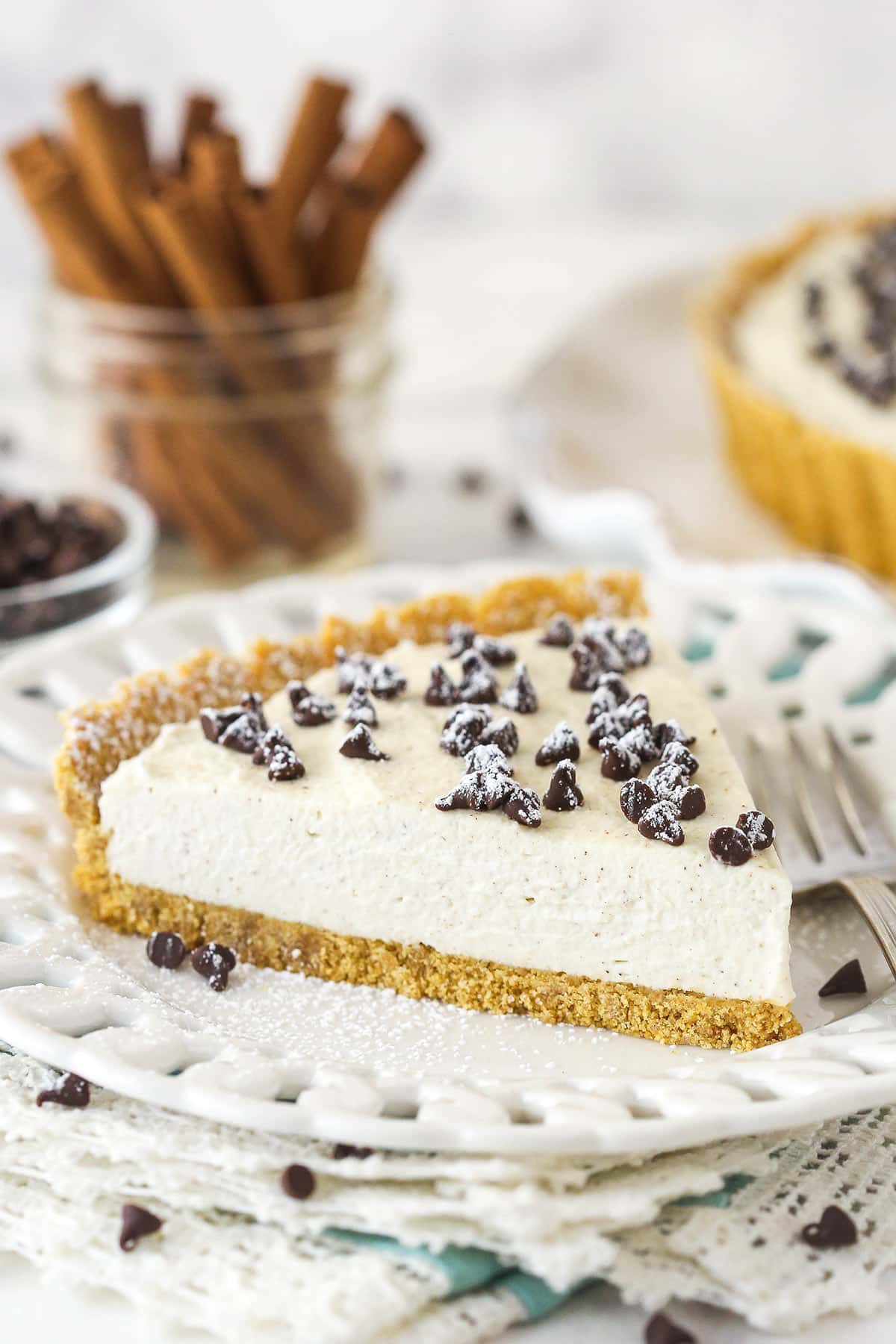 With a hint of cinnamon and some mini chocolate chips, this cannoli tart has all the great flavors of a cannoli wrapped into one simple tart. A slice of cannoli tart on a plate.