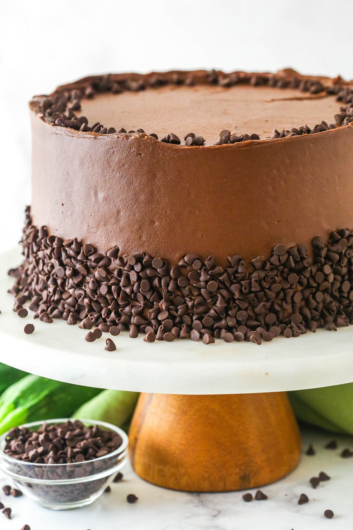 This Chocolate Zucchini Cake is so dreamy! 3 moist, zucchini-loaded chocolate cake layers are filled and frosted with chocolate buttercream. Zucchini chocolate cake on a cake stand.