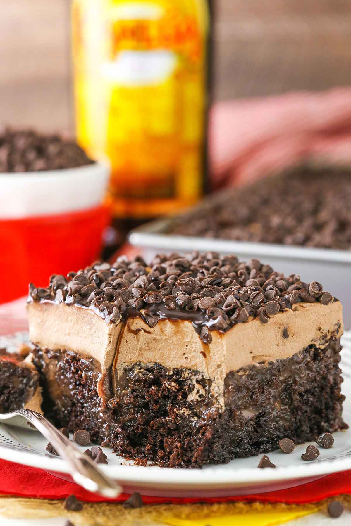 A square slice of Kahlua Chocolate Poke Cake on a white plate with a bite removed