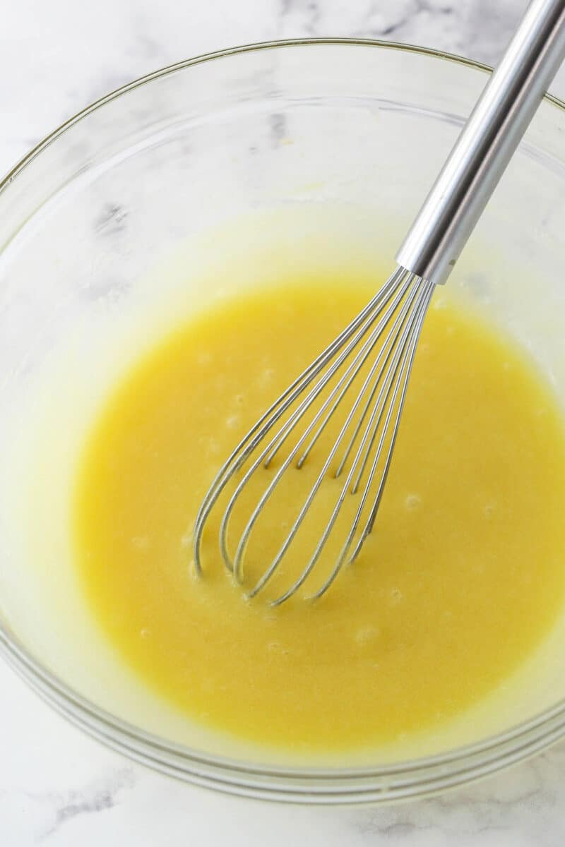 Whisking eggs and vanilla into sugar and melted butter.