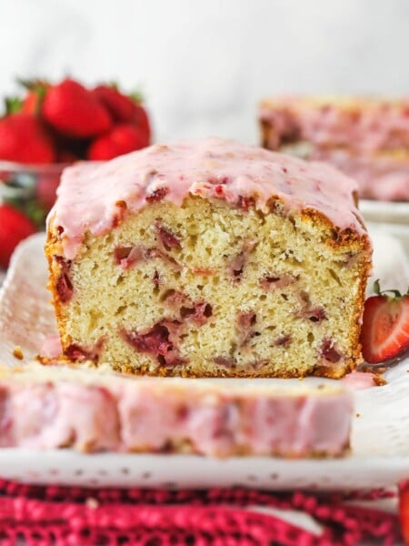 Strawberry bread on a serving platter with a slice cut out of it.