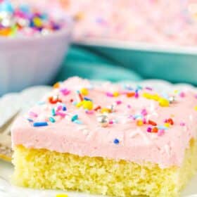 A square slice of Vanilla Sheet Cake next to a fork on a white plate