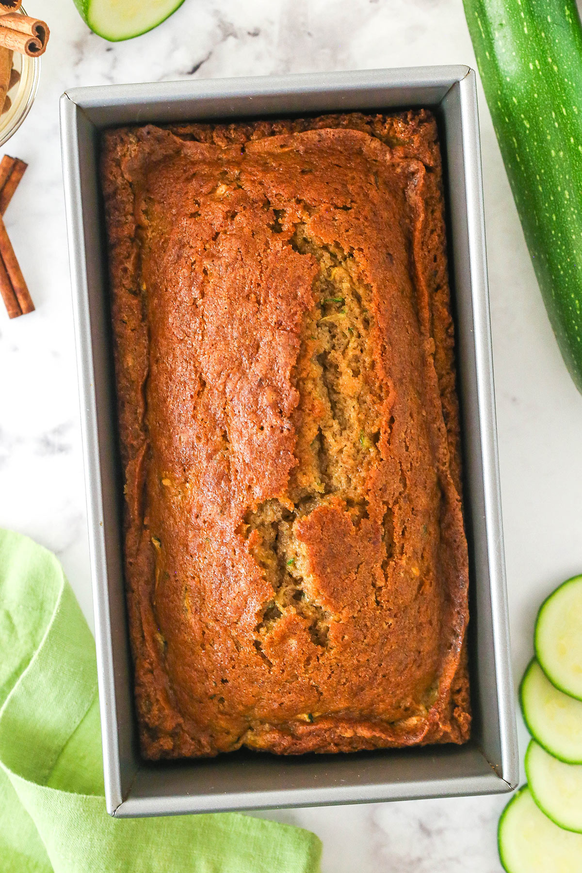 When life gives you zucchini, make this zucchini bread! It's so moist, the perfect amount of sweet, and has a subtle hint of cinnamon to it. Overhead image of zucchini bread in a loaf pan.