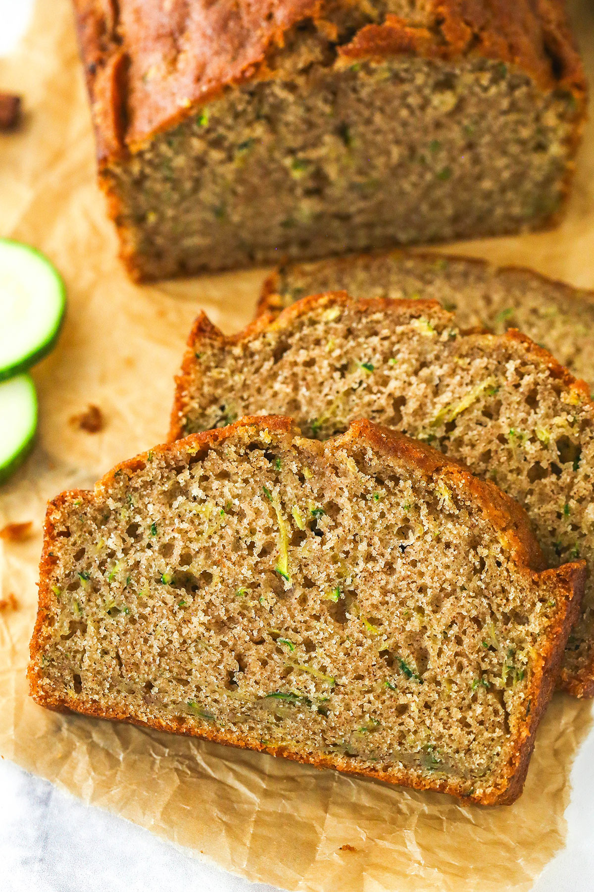 When life gives you zucchini, make this zucchini bread! It's so moist, the perfect amount of sweet, and has a subtle hint of cinnamon to it. Overhead image of zucchini bread cut into slices on a cutting board.