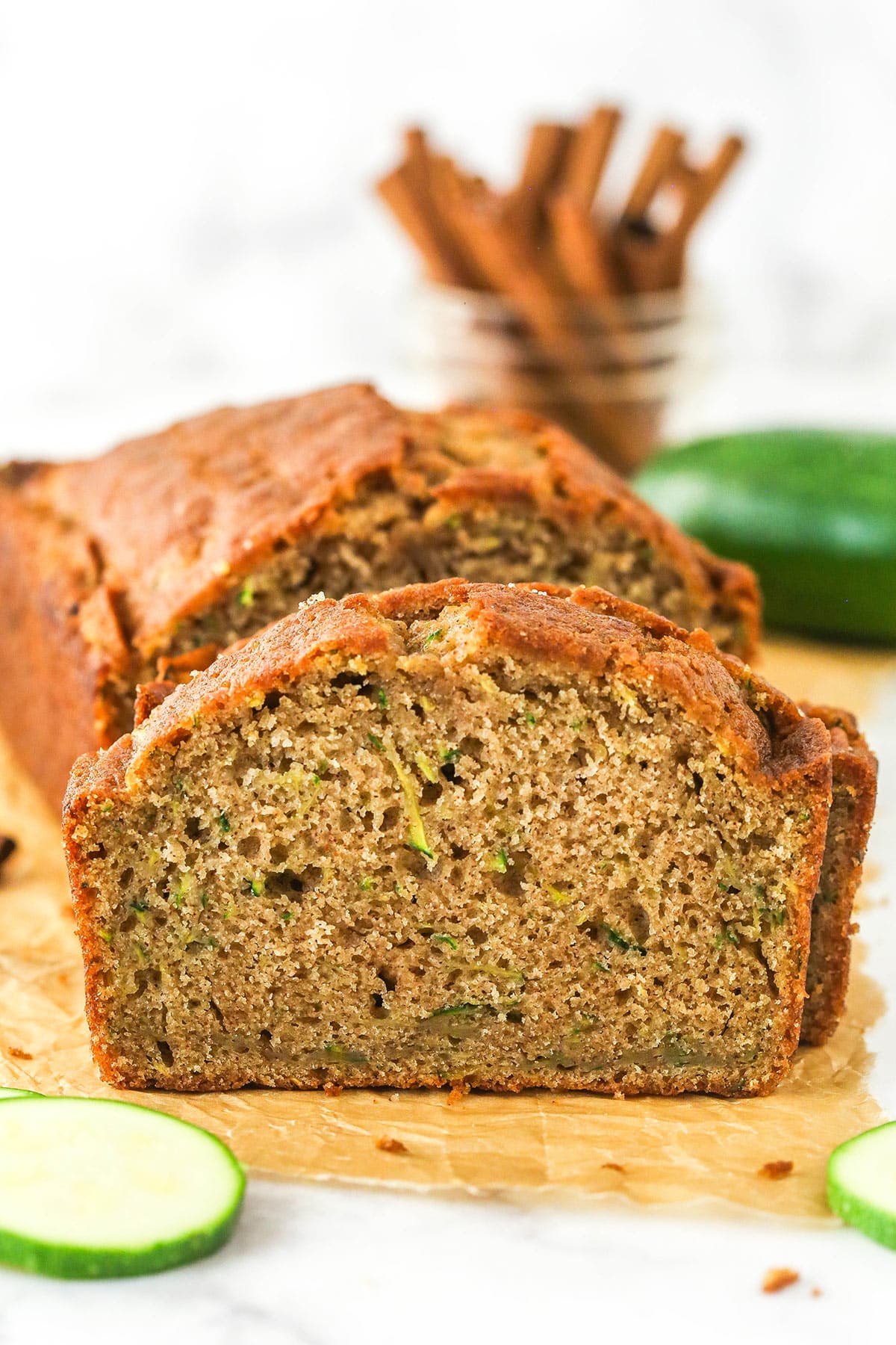 When life gives you zucchini, make this zucchini bread! It's so moist, the perfect amount of sweet, and has a subtle hint of cinnamon to it. Zucchini bread cut into slices on a cutting board.