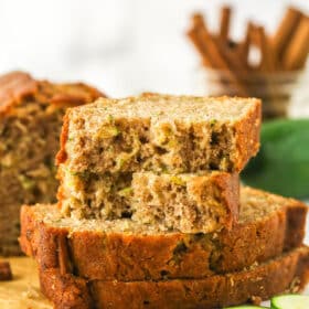 Sliced of zucchini bread stacked on top of each other. The top slice is torn in half.