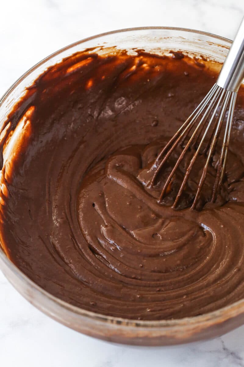 This Chocolate Zucchini Cake is so dreamy! 3 moist, zucchini-loaded chocolate cake layers are filled and frosted with chocolate buttercream. Combining the wet and dry ingredients for chocolate cake batter.