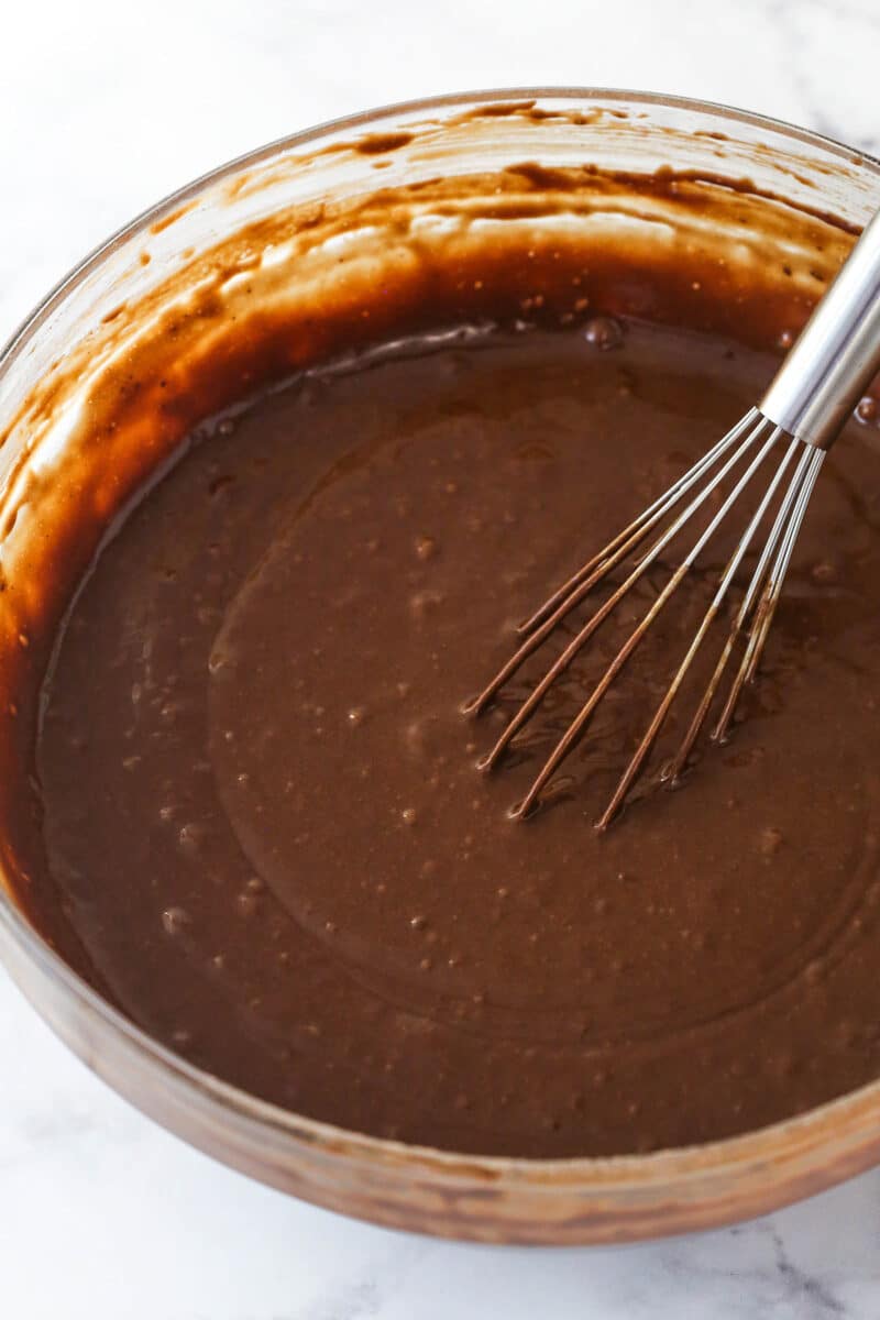 This Chocolate Zucchini Cake is so dreamy! 3 moist, zucchini-loaded chocolate cake layers are filled and frosted with chocolate buttercream. Mixing hot water into chocolate cake batter.