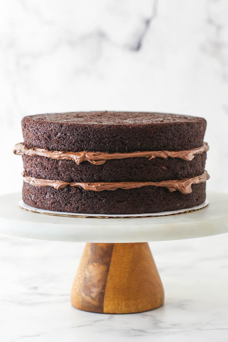 This Chocolate Zucchini Cake is so dreamy! 3 moist, zucchini-loaded chocolate cake layers are filled and frosted with chocolate buttercream. Stacking and filling chocolate zucchini layer cake.