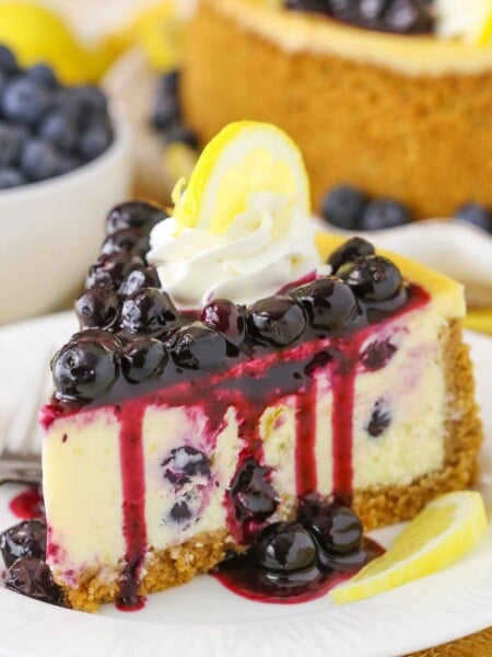 Side view of a slice of Lemon Blueberry Cheesecake on a white plate