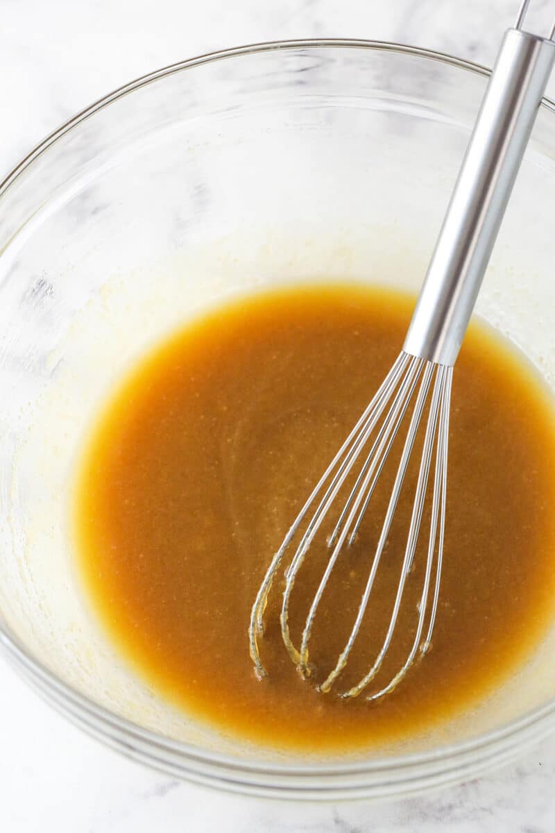 A mixing bowl with caramel sauce and a whisk in it.