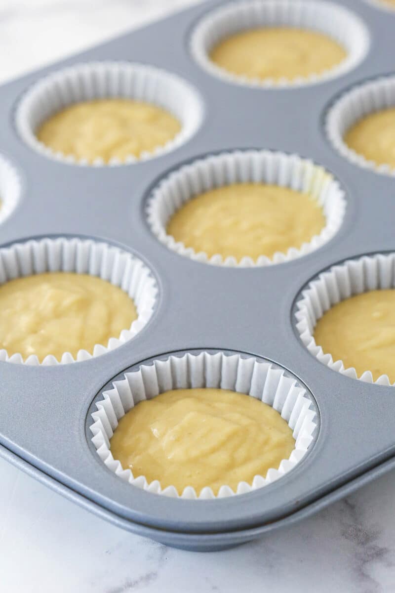 A cupcake pan lined with filled with cupcake batter.