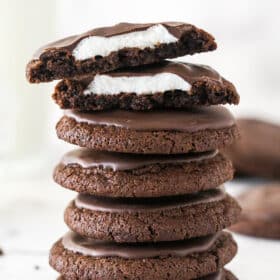 A stack of chocolate marshmallow cookies, with one cut in top on half to show the marshmallow inside