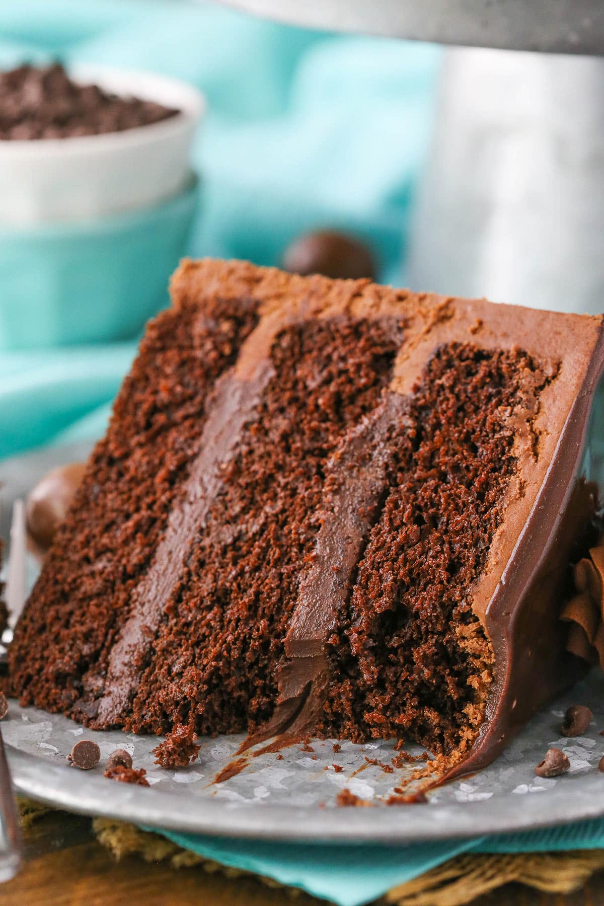 This Drunken Chocolate Truffle Cake is made with a moist chocolate cake recipe, chocolate truffle filling & chocolate frosting - all infused with chocolate liqueur for a delicious "drunken" cake! A slice of Drunken Chocolate Truffle Cake with a bite removed on a gray plate