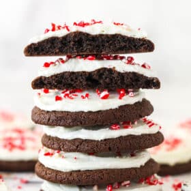 A stack of Peppermint Frosted Chocolate Cookies with the top cookie cut in half to show texture.