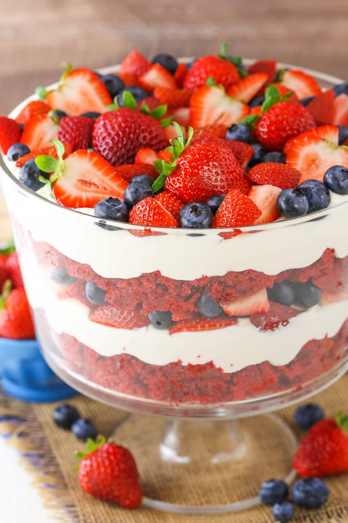 This Red Velvet Berry Trifle recipe is made with layers of moist red velvet cake, fresh berries and homemade cream cheese whipped cream! It's such a light dessert that's easy to make and full of flavor! A full Red Velvet Berry Trifle in a clear glass trifle bowl