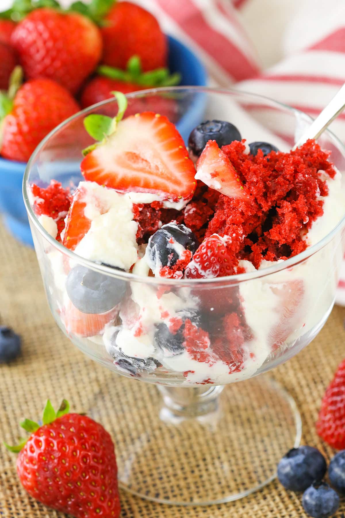 This Red Velvet Berry Trifle recipe is made with layers of moist red velvet cake, fresh berries and homemade cream cheese whipped cream! It's such a light dessert that's easy to make and full of flavor! A serving of Red Velvet Berry Trifle in a glass bowl