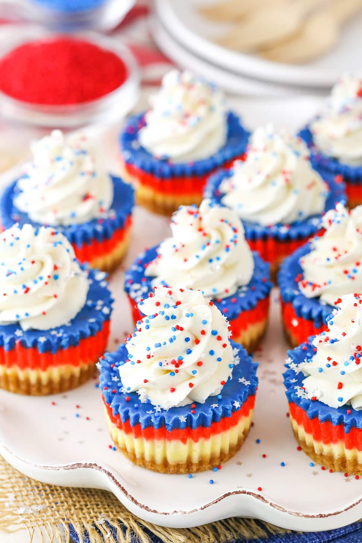 These Red, White and Blue Mini Cheesecakes are smooth, creamy and easy to make! Perfect for your patriotic celebration! Red White and Blue Mini Cheesecakes on a white platter