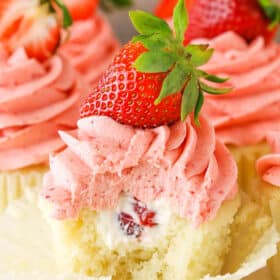 A Strawberries and Cream Cupcake with a bite removed