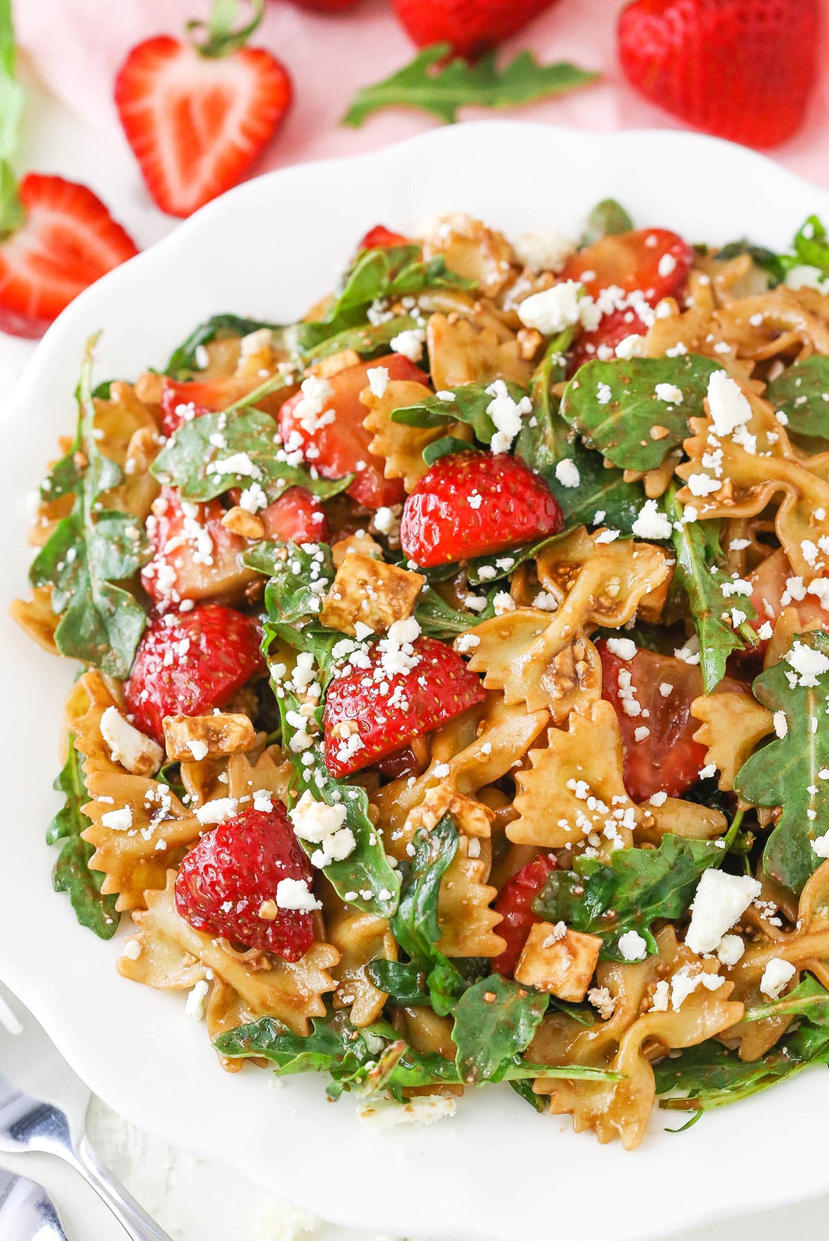 This Strawberry Feta Balsamic Pasta Salad is easy to make, fresh and delicious for summer! It's so many of my favorite things in one! Overhead view of Strawberry Feta Balsamic Pasta Salad on a white plate