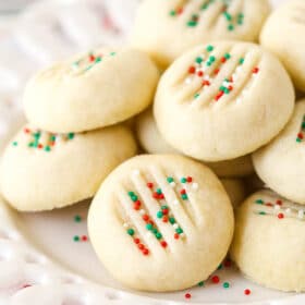A pile of whipped shortbread cookies on a white plate