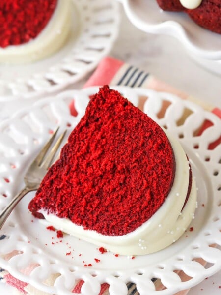 Overhead view of a slice of red velvet bndt cake on a white plate