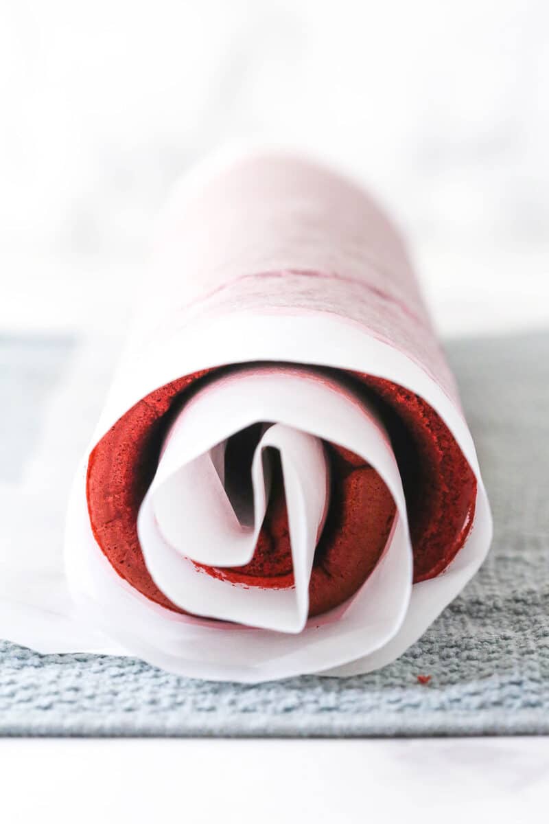 This red velvet cake roll is light and tender with the signature tang and hint of chocolate flavor. Perfect for Christmas & Valentine's Day! Red velvet cake rolled in parchment paper