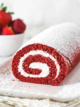 Front view of red velvet cake roll on a white platter