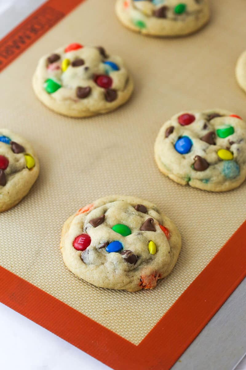 M&M cookies cooling on a silicon baking sheet.