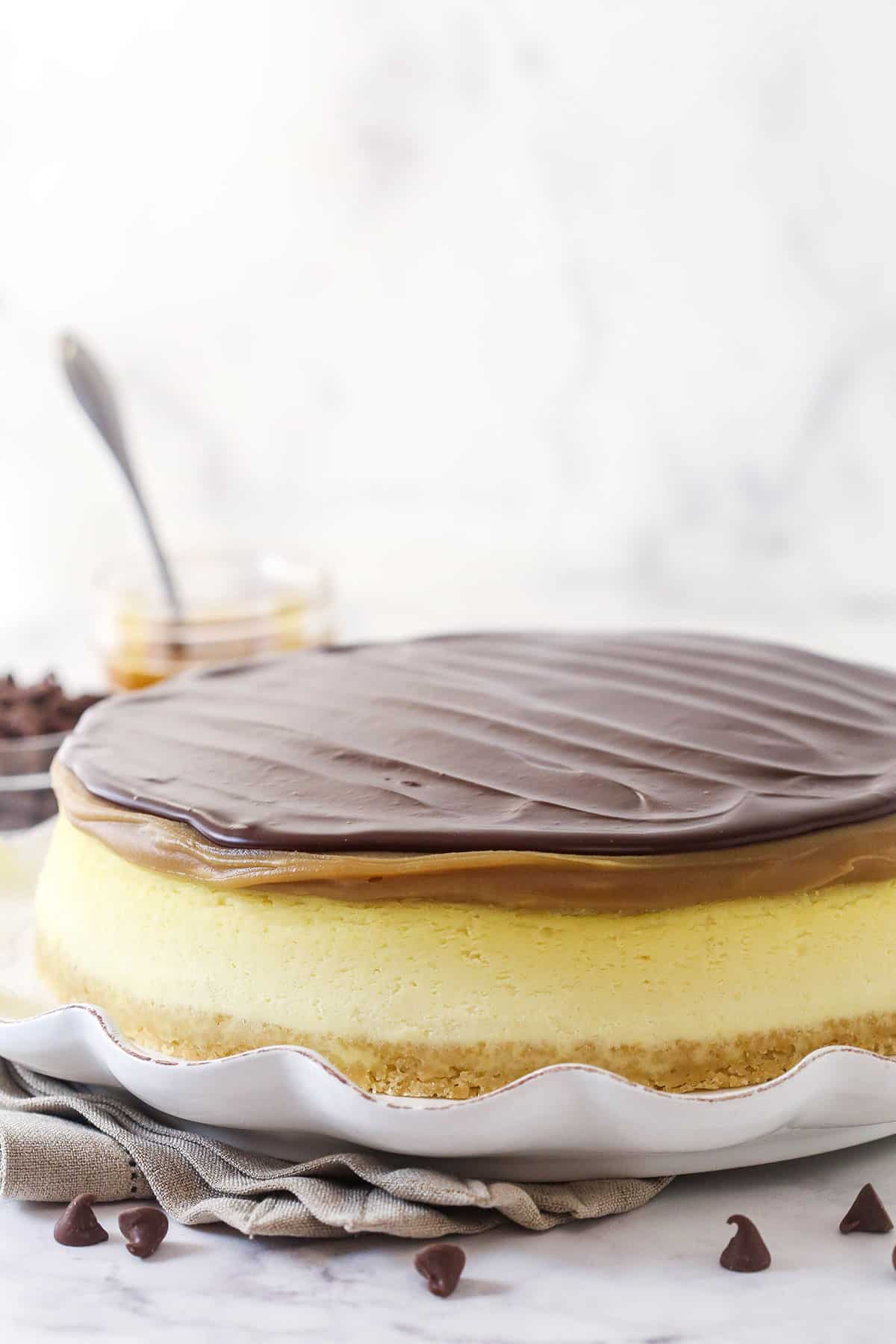 This Millionaire Cheesecake is next level! It's a tangy cheesecake doused in caramel and chocolate ganache atop a buttery shortbread crust. Millionaire cheesecake on a serving platter.