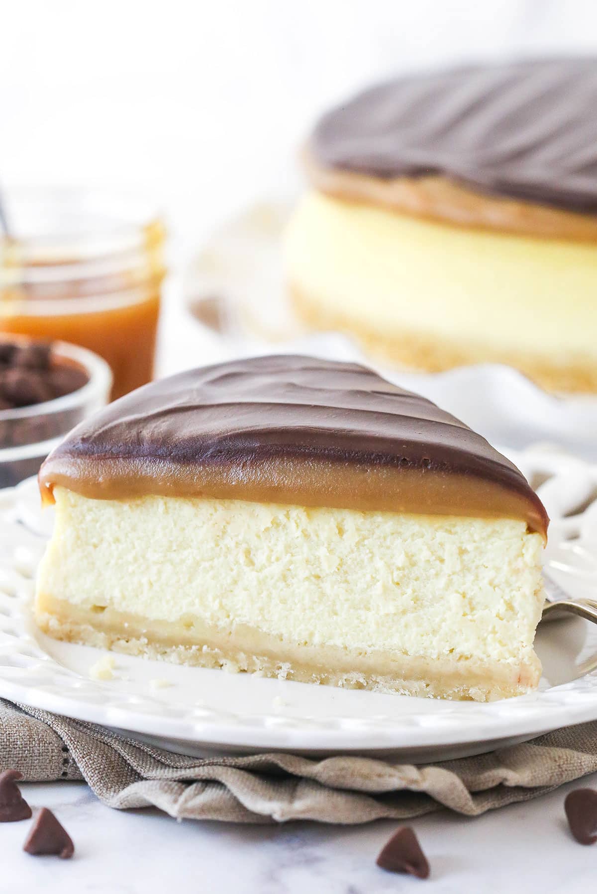 This Millionaire Cheesecake is next level! It's a tangy cheesecake doused in caramel and chocolate ganache atop a buttery shortbread crust. A slice of millionaire cheesecake on a plate.