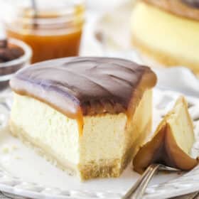 A slice of millionaire cheesecake on a plate with a bite taken out of it.