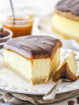 A slice of millionaire cheesecake on a plate with a bite taken out of it.