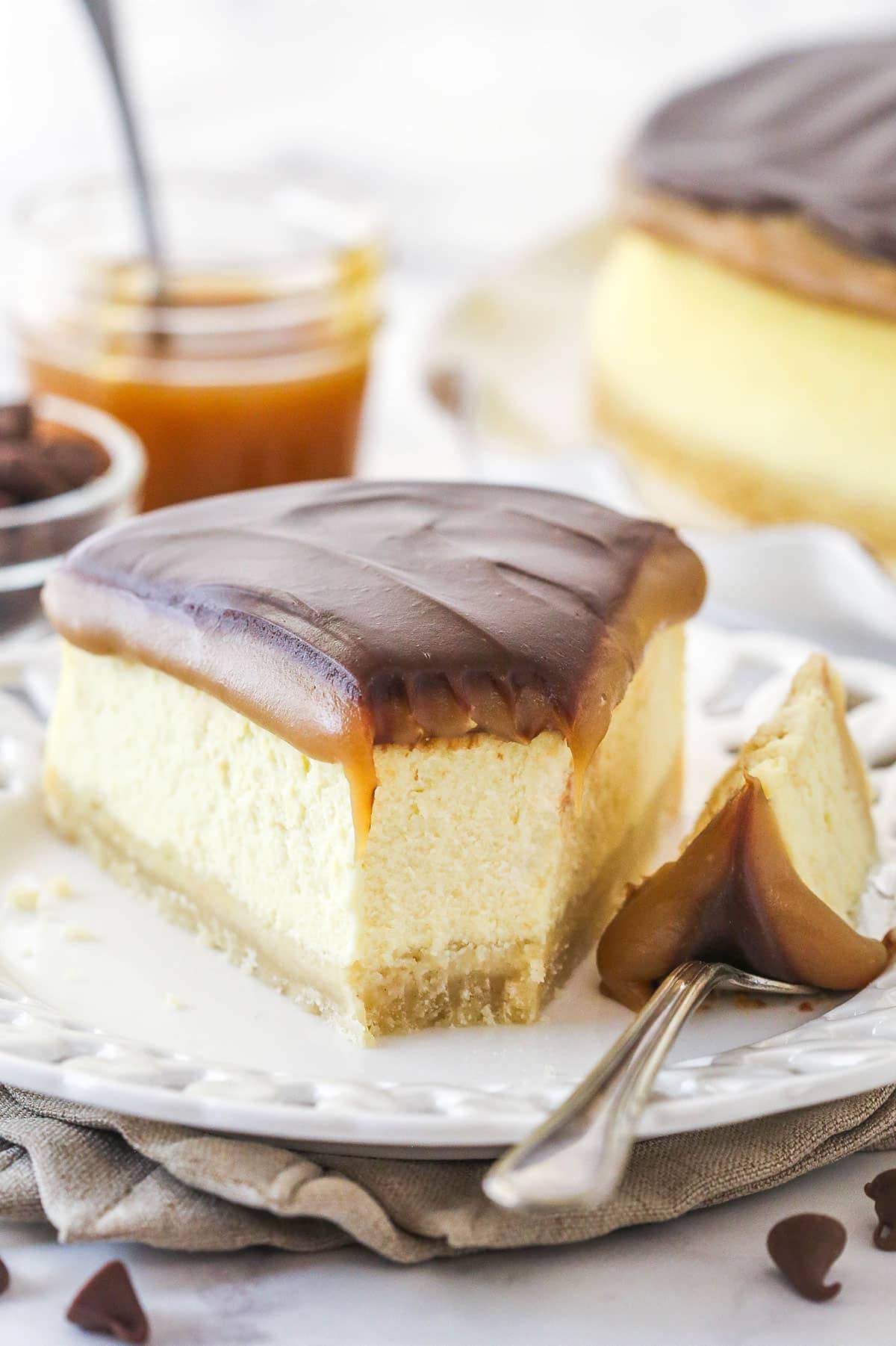 This Millionaire Cheesecake is next level! It's a tangy cheesecake doused in caramel and chocolate ganache atop a buttery shortbread crust. A slice of millionaire cheesecake on a plate with a bite taken out of it.